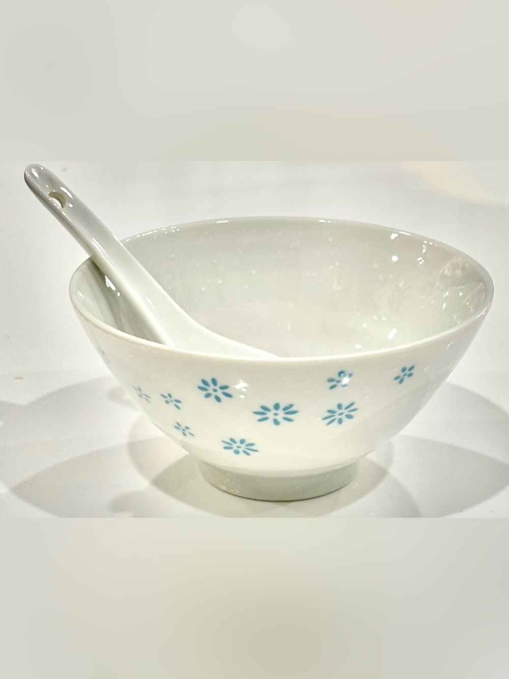 White Ceramic Bowl with Blue Floral Motif on Exterior and Matching Spoon